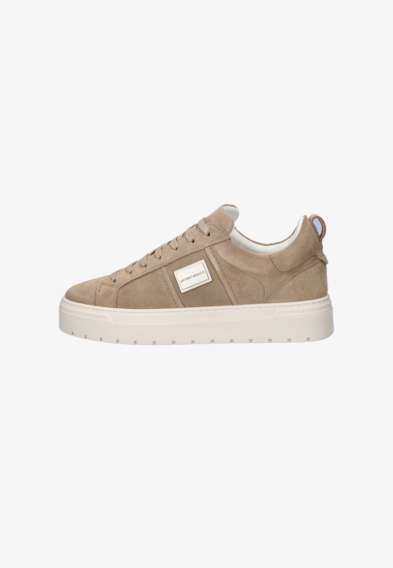 Beige suède lage sneaker met veters aan de voorkant, dikke witte rubberen zool, trekkoord aan de hiel en een klein rechthoekig merkembleem aan de zijkant.