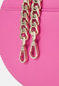 Borsa a tracolla in pelle sintetica rosa con un design arrotondato, dettagli in catena dorata e fibbie girevoli. Texture liscia con cuciture a contrasto.