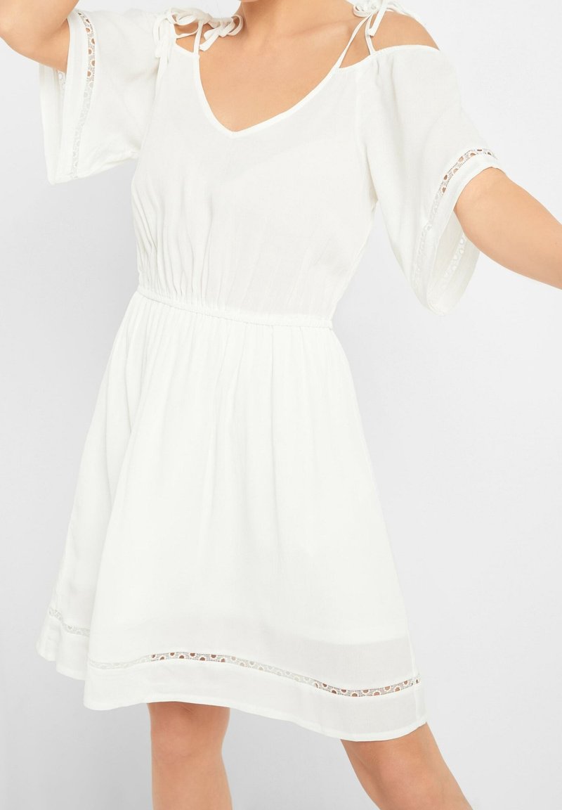 Vestito bianco a maniche corte con scollatura a V, spalline regolabili e vita arricciata. Presenta una finitura in pizzo all'orlo e alle maniche.