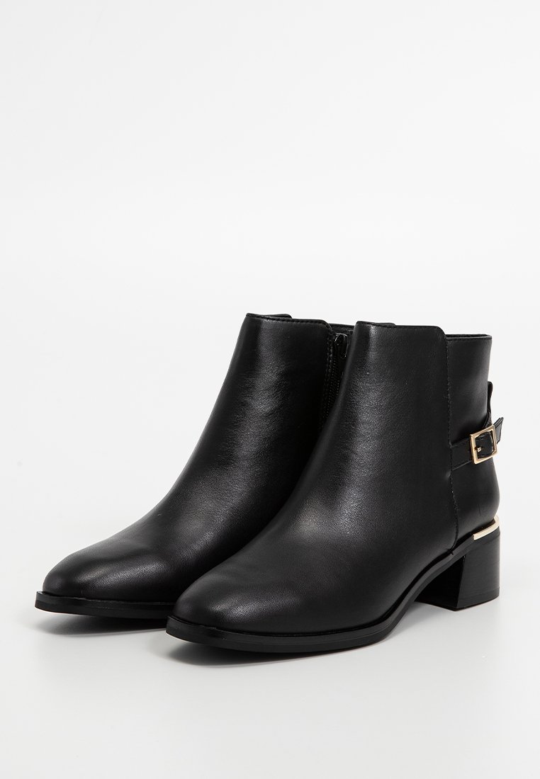 Bottines en cuir noir avec un bout pointu, fermeture éclair sur le côté, petit talon bloc et un accent en métal doré sur le côté.