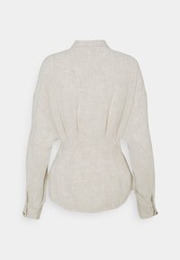 Chemise en lin beige à manches longues avec col, comportant des plis dans le dos et des poignets boutonnés. Texture lisse avec une coupe décontractée.