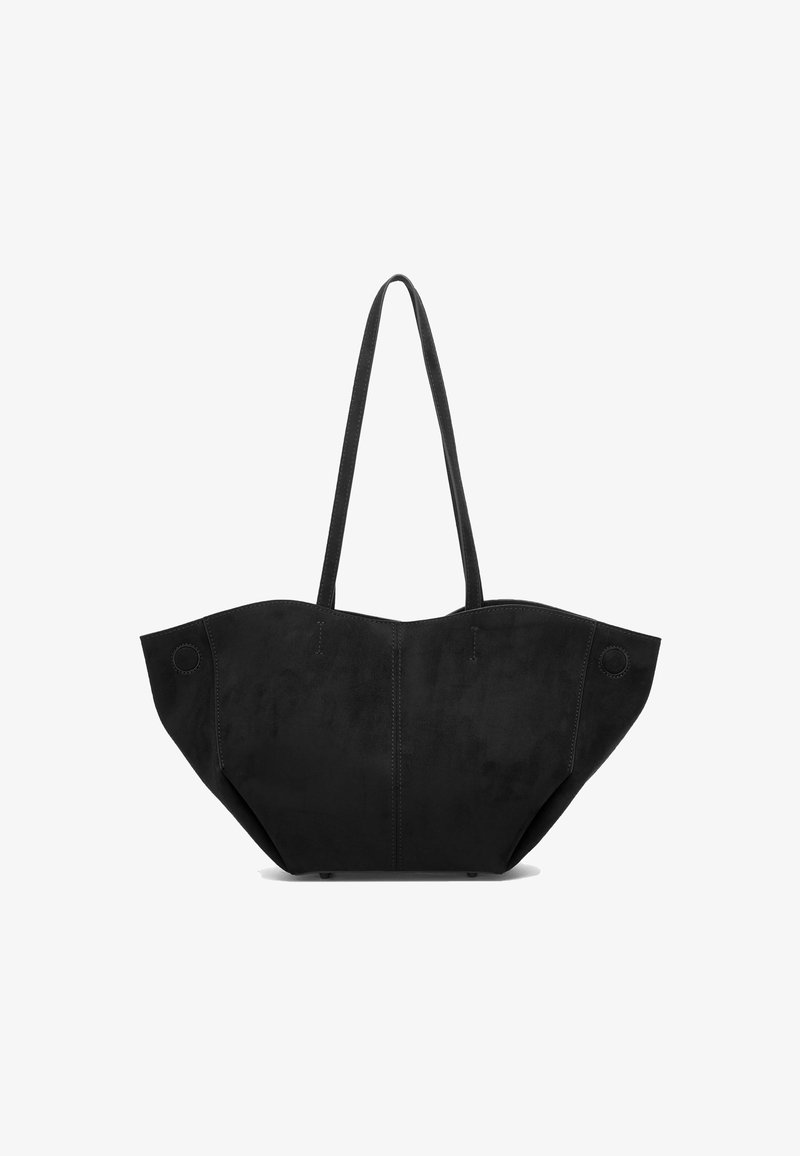 Μαύρη suede τσάντα tote με δομημένο, γωνιώδη σχήμα, που διαθέτει δύο μακριές λαβές και κυκλικά διακοσμητικά στοιχεία στις πλευρές.