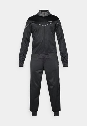 Zwarte sportieve trainingspak gemaakt van gladde stof. Bevat een jack met ritssluiting en hoge kraag, en bijpassende broek met geribde boorden en witte accenten.