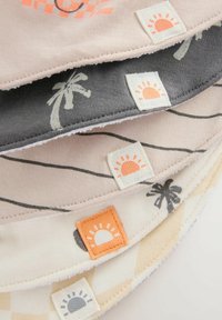 Tissus en coton de couleur pêche, gris et crème avec des motifs de palmiers et d'icônes de soleil, comportant des étiquettes tissées sur les bords.