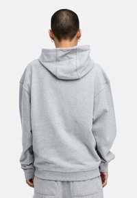 Hoodie in Hellgrau, mit lässiger Passform, gerippten Bündchen und Saum sowie weichem, strukturiertem Stoff. Keine sichtbaren Logos oder Muster.
