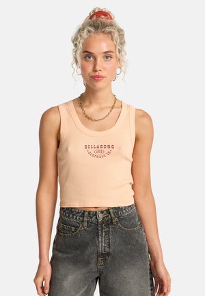 Top canotta color pesca con scollo arrotondato e grafica "Billabong". Abbinato a jeans neri sbiaditi a vita alta.