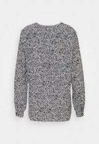 Lässiges Langarm-Oberteil in Weiß mit einem schwarzen abstrakten Druck, das über einen runden Halsausschnitt und geraffte Ärmel für zusätzliche Struktur verfügt.