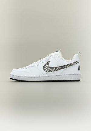 Λευκό χαμηλό σπορ παπούτσι Nike με ασπρόμαυρο ζωγραφιστό λογότυπο ζέβρας και μαύρη λεπτομέρεια στη σόλα σε απλό γκρι φόντο.
