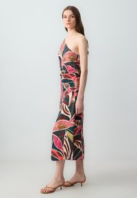 Ein schulterfreies Kleid mit lebhaftem Blumenmuster, das pinke, grüne und goldene Farben auf schwarzem Hintergrund zeigt. Hergestellt aus weichem Stoff, knielanges Design.