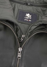 Schwarze Lederjacke mit einer grauen isolierten Fütterung, doppelten Reißverschlüssen und einem Etikett mit einem Löwen-Logo, die ein elegantes Design und eine ansprechende Textur präsentiert.