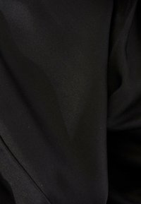 Tissu noir lisse avec des plis subtils et une texture douce visible en gros plan.