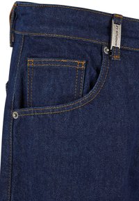 Jean en denim bleu foncé avec une poche avant, des coutures orange, des accessoires en métal et une étiquette de marque sur la ceinture.