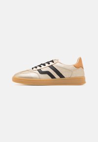 Gold synthetic sneaker with black stripes, lace closure, and a tan heel accent. Features a textured gum sole and flat design.