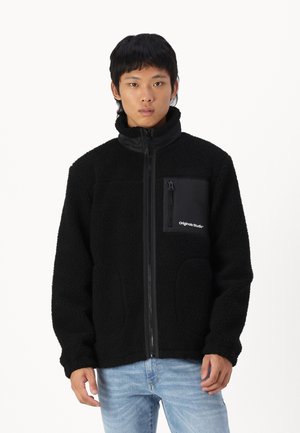 Black fleece jacket with zip front, high collar, and a chest pocket. Textured fabric and two side pockets. Casual design.