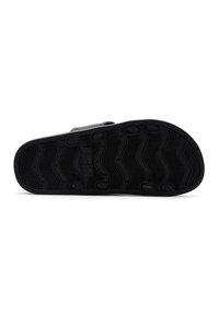 Suela de zapato de goma negra con un diseño de banda de rodadura en forma de ola, con acentos de agarre circulares y un borde liso para brindar estabilidad y tracción.