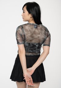 Sheer gray top with black accents, featuring a subtle pattern, short sleeves, and a round neckline, paired with a black skirt.