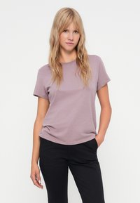Korte mouwen, ronde hals t-shirt in zachte lavendelstof, met een relaxed fit en een gladde textuur, gecombineerd met zwarte broek.