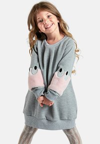 Robe sweat grise avec des patchs en fourrure rose aux coudes présentant des yeux. Matière douce, manches longues et ourlet arrondi. Leggings à motifs en dessous.
