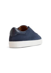 Sneaker in suede blu navy con un contrastante tab sul tallone in pelle blu navy. Presenta una suola in gomma bianca e dettagli testurizzati lungo il retro.