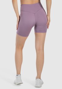 Bermudas deportivas moradas de talle alto con una textura suave y un diseño ajustado, que presentan una longitud a mitad del muslo y un mínimo detalle de costuras.