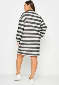 Grå och vit randig oversized klänning med långa ärmar, hög krage och avslappnad passform, kombinerad med vita plattformssneakers.