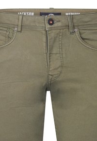 Jean en denim vert olive avec poches avant, fermeture à bouton et zip. Détails cousus le long des coutures et étiquette de marque à l'intérieur de la taille.