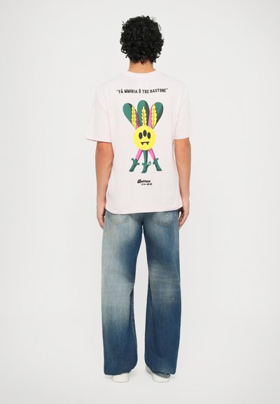 Roze katoenen T-shirt met een grafische print van een gele gezicht en kleurrijke accenten op de achterkant, gecombineerd met wijde blauwe denim jeans.