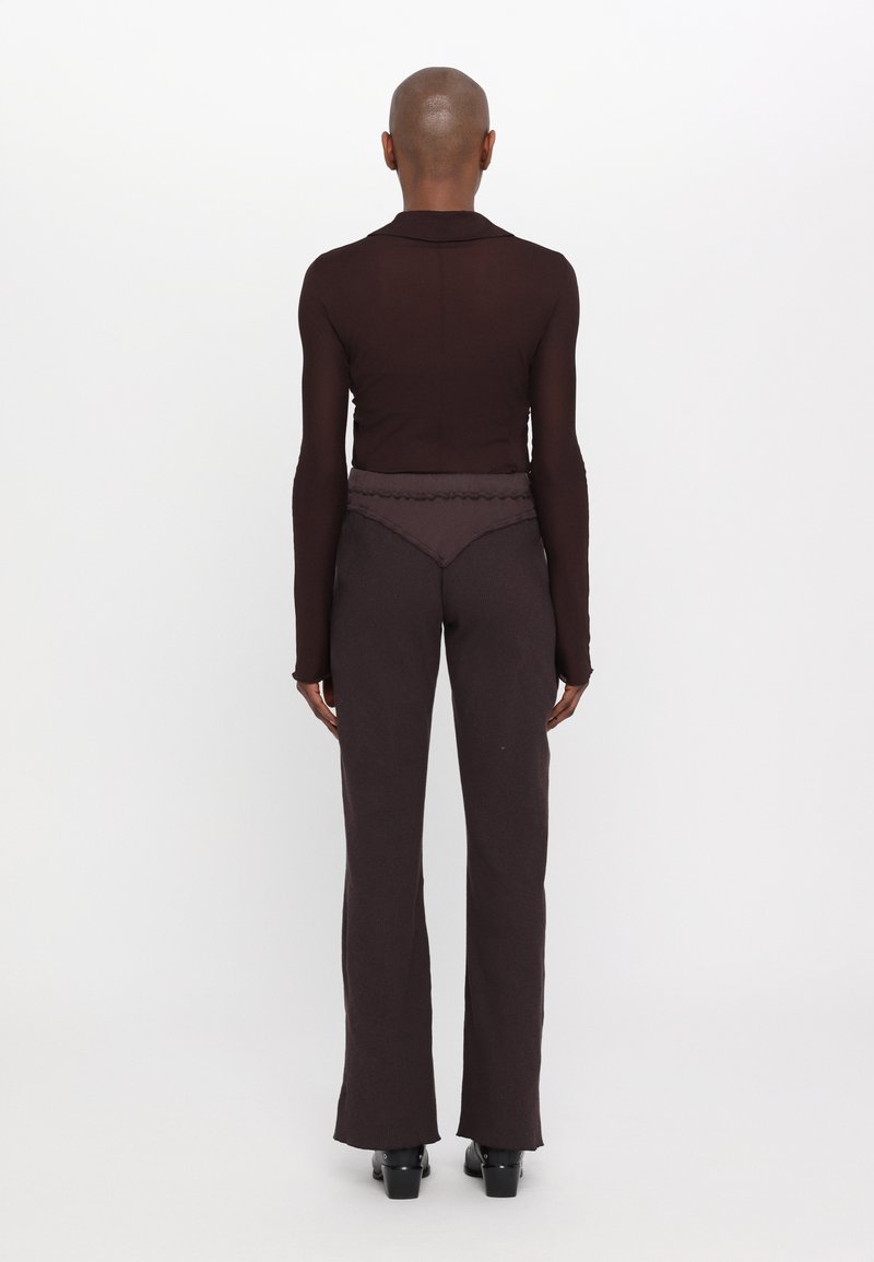 Top marrón transparente, de manga larga y ajustado, con cuello, combinado con pantalones acampanados de talle alto en marrón oscuro. Textura suave, con detalles mínimos.