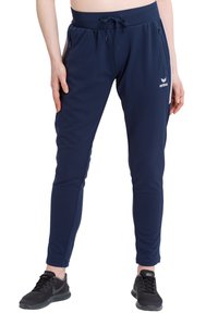 Marineblauwe sportbroek met een verstelbare tailleband, ritszakken aan de zijkant, taps toelopende pijpen en een geborduurd logo op de linkerbovenkant.