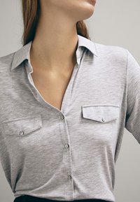 Graues Button-Up-Hemd aus weichem Stoff, mit Kragen, zwei Brusttaschen mit Knopfverschluss und einer lockeren Passform.