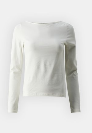 Pikendusega särk heleda puuvilla ees. Omab ümmargust kaelust ja sujuvat tekstuuri, millel on minimaalne õmbluste detail.