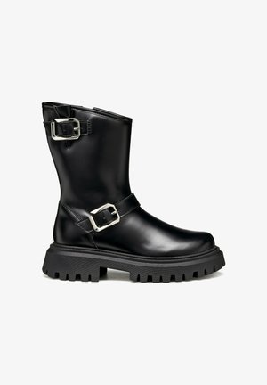 Stivale alla caviglia in pelle nera con due fibbie d'argento, suola spessa e strutturata e punta leggermente arrotondata. Presenta una finitura liscia e un design robusto.