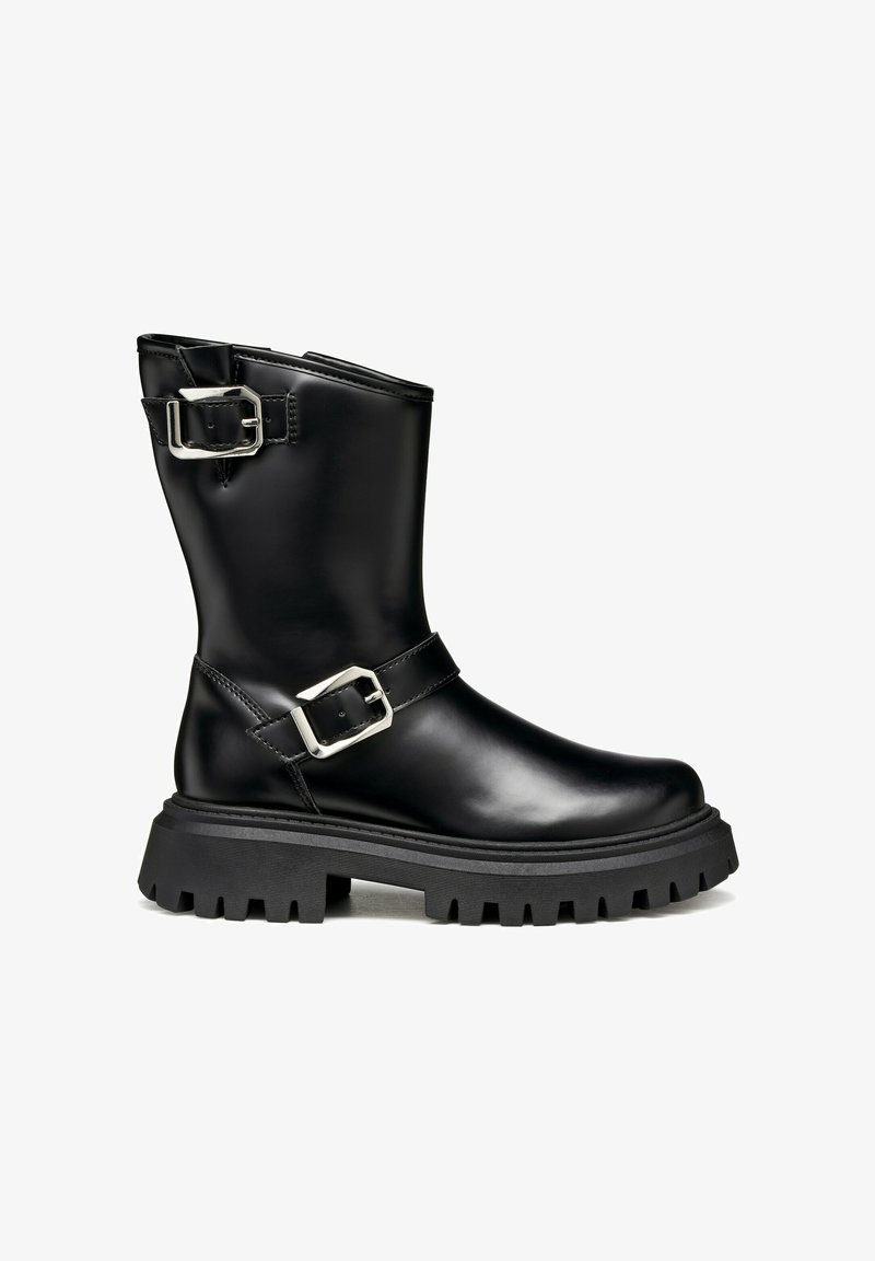 Bota de tobillo de cuero negro con dos hebillas plateadas, una suela gruesa y texturizada, y una puntera ligeramente redondeada. Presenta un acabado suave y un diseño robusto.