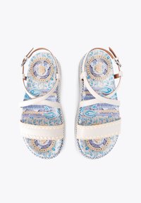 Białe sandały na paski z wzorzystą niebieską wkładką, ozdobione skomplikowanymi wzorami oraz tkanym teksturowanym spodem dla dodatkowego efektu.