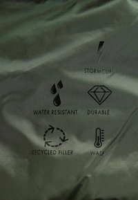 Tessuto resistente all'acqua con icone per Stormcuff, durata, imbottitura riciclata e calore, caratterizzato da una superficie liscia e texture.