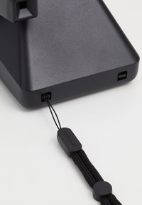 Black rectangular device with a textured surface, side ports, and a black string attached featuring a round tag labeled "Polaroid."