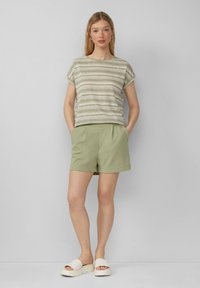 Paski krótki top z krótkim rękawem w kolorze kremowym i oliwkowym z podwiniętymi rękawami, połączony z oliwkowymi szortami i kremowymi platformami.