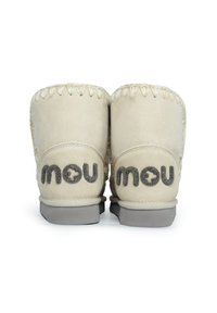 Botas de ante beige hasta el tobillo con una textura suave, con un diseño cosido y suelas de goma gris. Logo "mou" en la parte posterior.