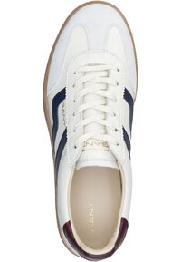 Zapatilla blanca con detalles en azul marino y burdeos. Fabricada en cuero y ante, con un upper texturizado, punta redonda y suela de goma.