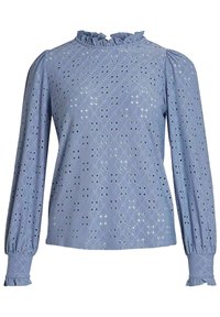 Vaaleansininen paita, jossa on pitkät pufferihihat, röyhelökaulus ja monimutkaiset aukkomuotoilut. Pehmeä, teksturoitu kangas ja gathers- hihansuut.