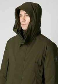 Olijfgroene capuchonjas met een rits aan de voorkant, twee zijzakken en een zachte textuur, voorzien van een logopatch op de linker mouw.