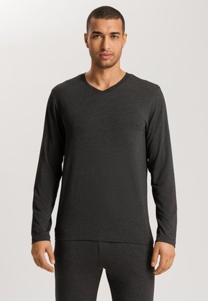 Zwarte langemouwen v-hals shirt van zachte stof, met een ontspannen pasvorm en subtiele textuur. Gecombineerd met bijpassende broeken.