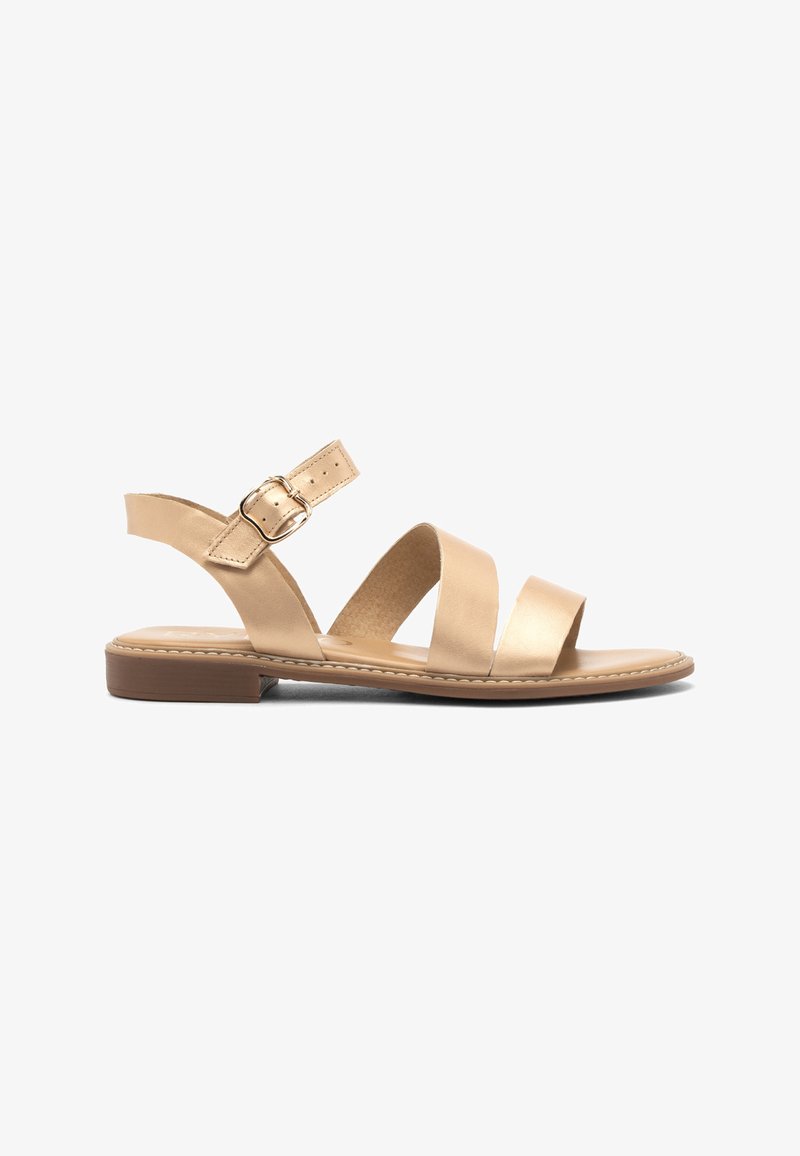 Sandal en cuir tan avec trois larges brides sur le pied, une bride de cheville ajustable avec une boucle en métal, et une semelle plate.