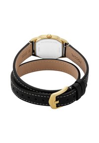 Montre-bracelet en cuir noir avec un boîtier octagonal en acier inoxydable doré, doublure intérieure de couleur crème, et fermeture à boucle avec couture blanche.