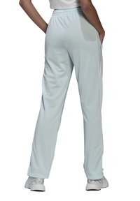 Lichtblauwe sportbroek met een ontspannen pasvorm, voorzien van een elastische tailleband, zijzakken en contrasterende witte strepen langs de zijkanten.