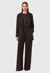 Abito marrone scuro, taglio morbido, composto da un blazer e pantaloni larghi. Tessuto morbido, design minimalista e senza motivi o accessori visibili.