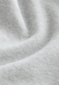 Miękka, jasnoszara tkanina o delikatnej fakturze i łagodnych fałdach, podkreślająca jej gładki i przytulny materiał.