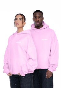 Ružové oversize mikiny s prednými vreckami, s voľným strihom, s kapucňou na šnúrky a bielym logom "MULTIPLY" na hrudi.