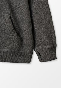 Mørkegrå sweatshirt med en tekstureret overflade, som har en frontlomme og ribbede manchetter. Den nederste side har en lille slidsdetalje.