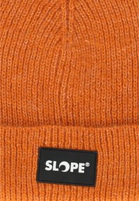 Orange strikket hue med ribbet tekstur, prydet med en sort rektangulær label med "SLOPE" logo. Det holdbare materiale og tætsiddende pasform fremhæver varmen.
